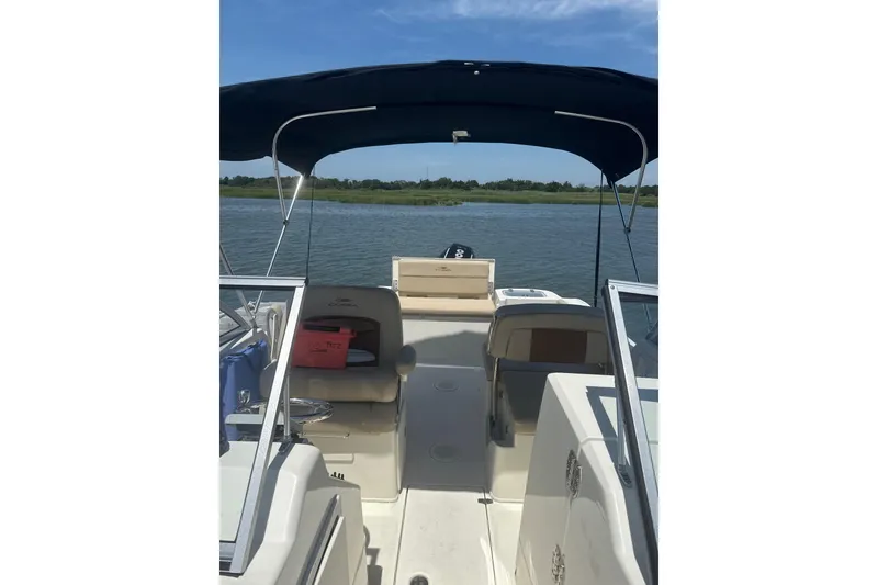 Slide: The Image of 2024 Cobia 220 Dual Console boat on calm water with canopy. - 5