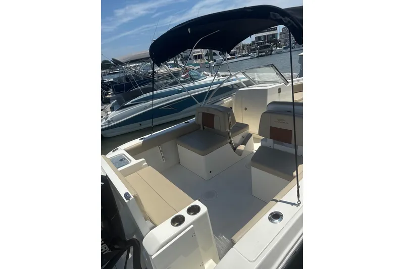Slide: The Image of 2024 Cobia 220 Dual Console boat with seating, docked at marina under sunny skies. - 9