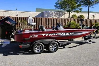Slide: The Image of 2025 Tracker Savage 215 boat on trailer, red and silver design, parked outdoors. - 4