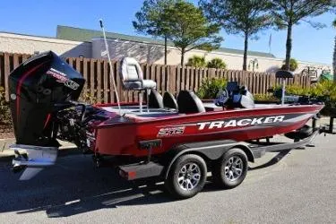 Slide: The Image of 2025 Tracker Savage 215 boat interior with red and gray seating, parked outdoors. - 8