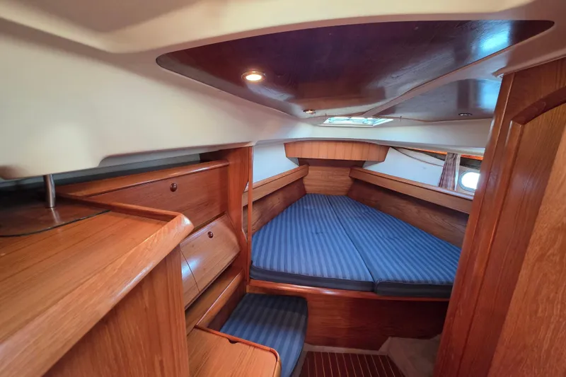 Slide: The Image of 1999 Jeanneau Sun Odyssey 40 DS cabin interior with wood finish and blue-striped bedding. - 13