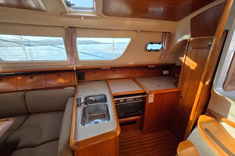 Slide: The Image of Interior of 1999 Jeanneau Sun Odyssey 40 DS sailboat, featuring a cozy kitchen and seating area. - 16