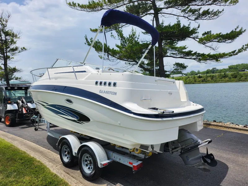 Slide: The Image of 2008 Glastron GT 249 boat on a trailer by a lake. - 1