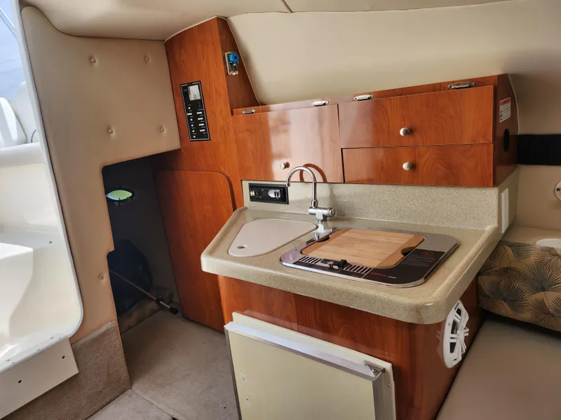 Slide: The Image of Compact kitchen area in 2008 Glastron GT 249 boat with sink, stove, and storage cabinets. - 22