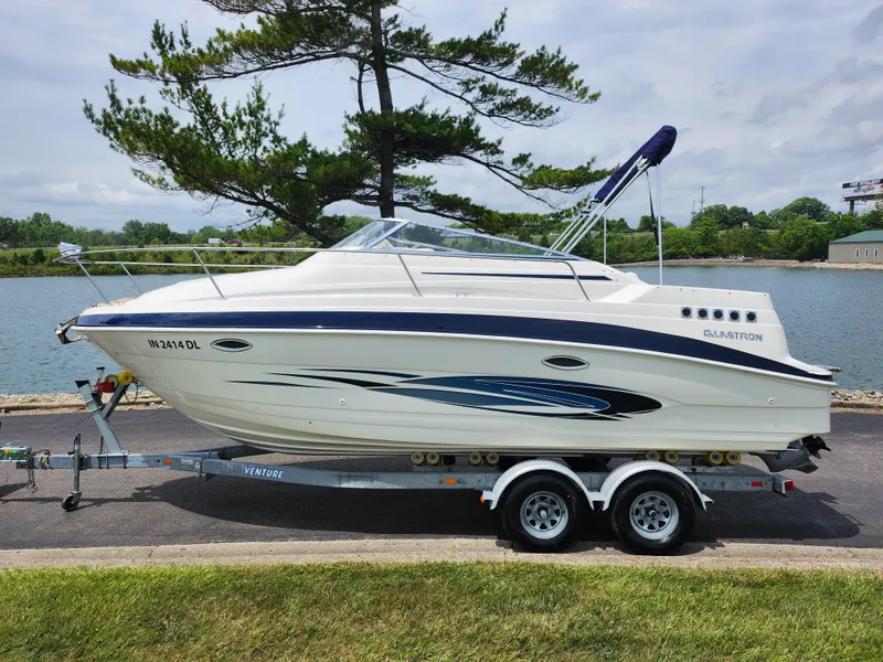 Slide: The Image of 2008 Glastron GT 249 boat on a trailer by a lake. - 9