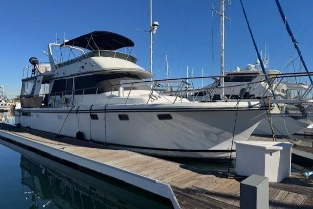 The Image of 1985 Symbol 58 Cockpit Motor Yacht docked at marina under clear blue sky. - 0