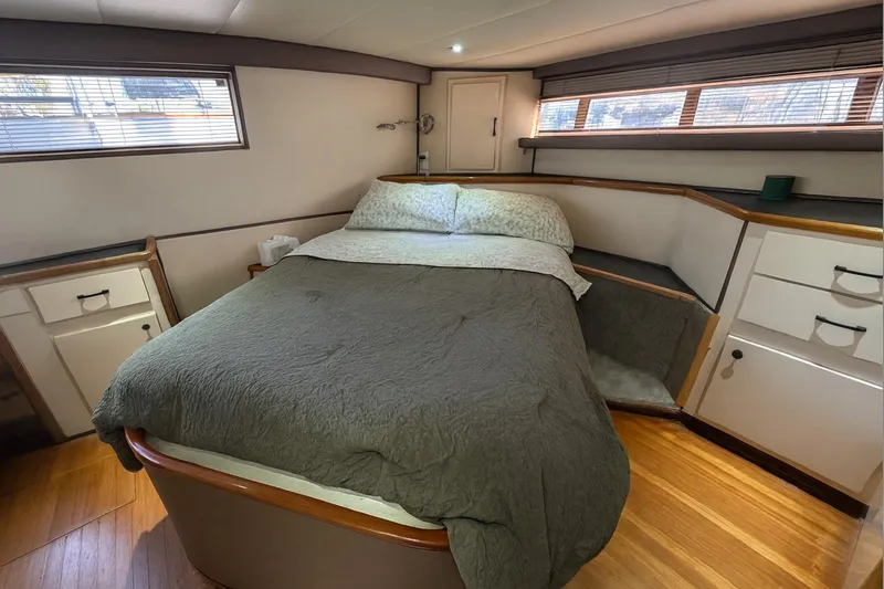 Slide: The Image of 1985 Symbol 58 Cockpit Motor Yacht bedroom with cozy bed and wooden cabinetry. - 22