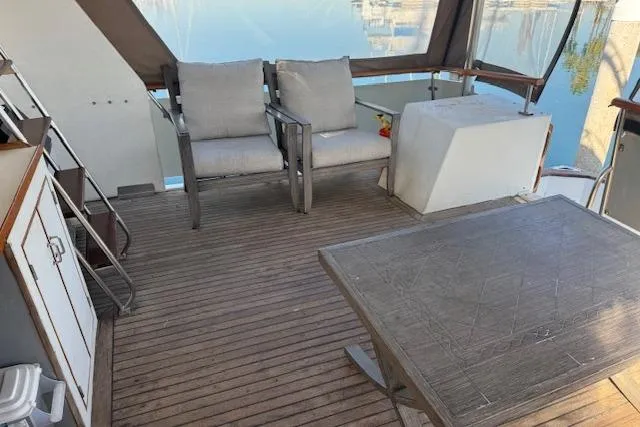 Slide: The Image of 1985 Symbol 58 Cockpit Motor Yacht interior with seating and table on wooden deck. - 4