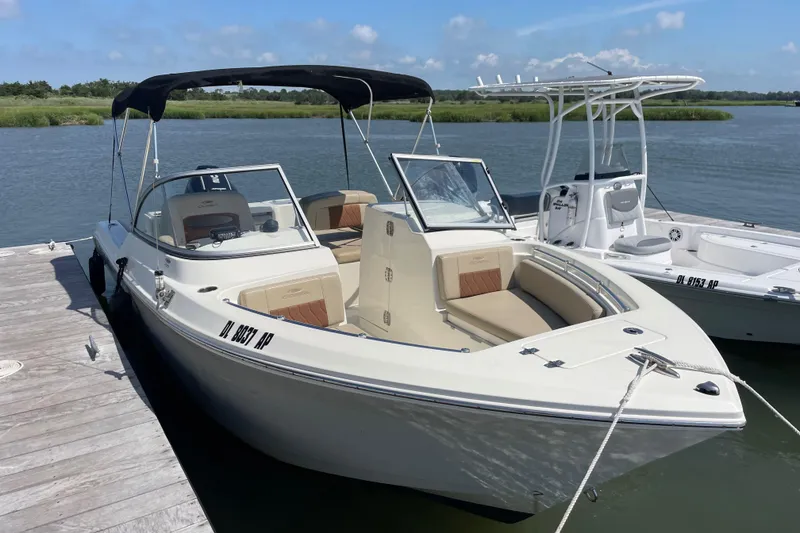 The Image of 2024 Cobia 220 Dual Console boat docked by the water on a sunny day. - 1
