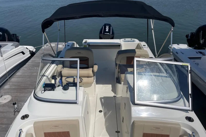 Slide: The Image of 2024 Cobia 220 Dual Console boat docked, featuring open seating and a black canopy. - 3