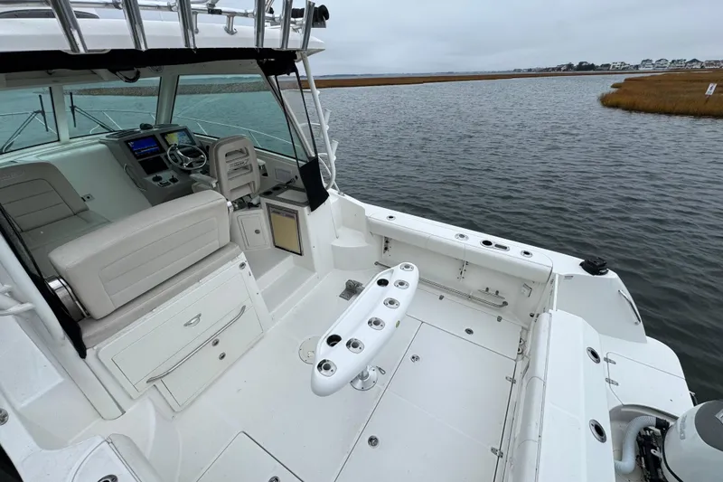 Slide: The Image of 2016 Boston Whaler 315 Conquest boat interior with helm and seating, docked on calm water. - 15