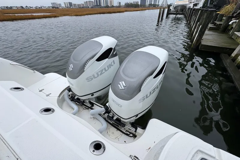 Slide: The Image of 2016 Boston Whaler 315 Conquest with twin Suzuki outboard engines docked by the water. - 16