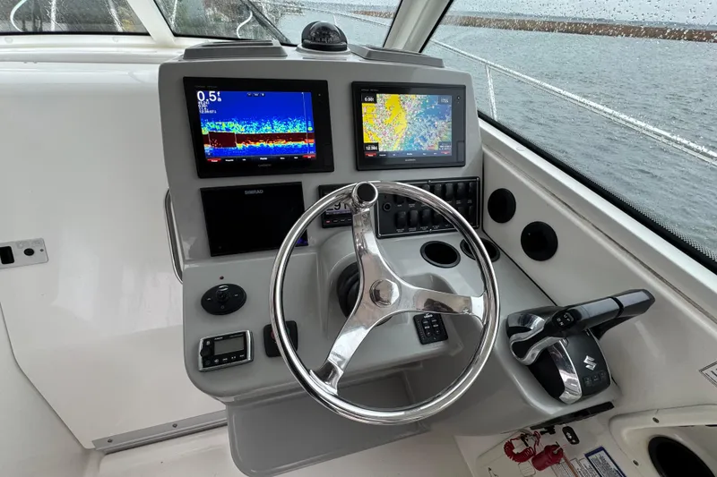 Slide: The Image of 2016 Boston Whaler 315 Conquest helm with dual navigation screens and steering wheel. - 22