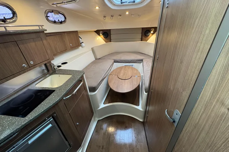 Slide: The Image of 2016 Boston Whaler 315 Conquest cabin interior with kitchenette and seating area. - 24