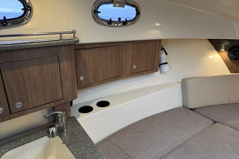Slide: The Image of Interior of 2016 Boston Whaler 315 Conquest, featuring wood cabinets and cozy seating area. - 28