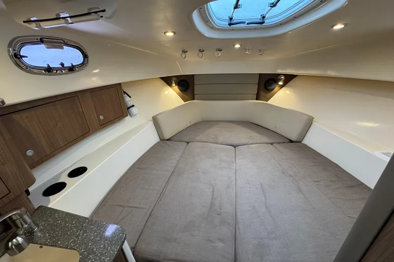 Slide: The Image of 2016 Boston Whaler 315 Conquest cabin interior with cozy bed and wooden cabinets. - 30