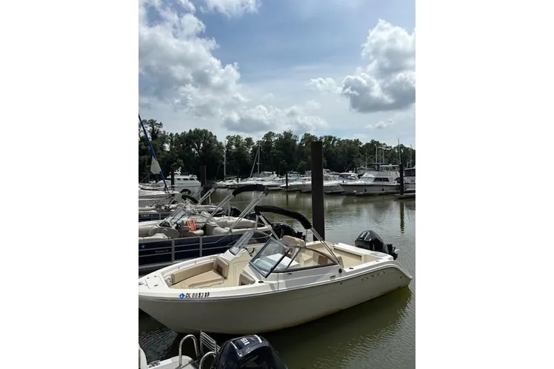 Slide: The Image of 2024 Cobia 220 Dual Console boat docked in a marina under a cloudy sky. - 4
