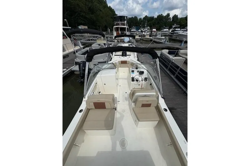 Slide: The Image of 2024 Cobia 220 Dual Console boat docked at marina, featuring spacious seating and modern design. - 5