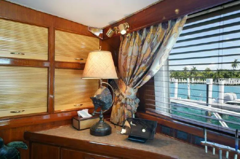 Slide: The Image of 1981 Bertram Convertible yacht interior with wooden cabinets, lamp, and ocean view. - 29