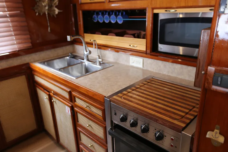 Slide: The Image of 1981 Bertram Convertible yacht kitchen with wooden cabinetry, double sink, and modern appliances. - 49