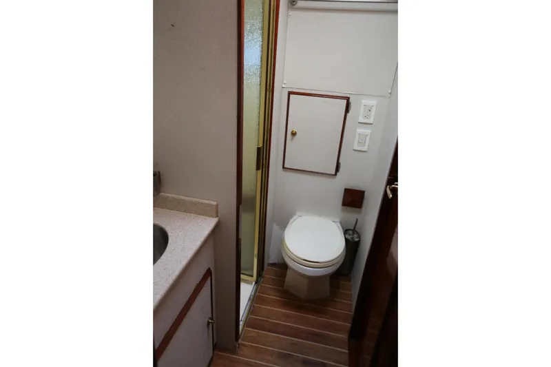 Slide: The Image of 1981 Bertram Convertible yacht bathroom with toilet, sink, and wooden flooring. - 57