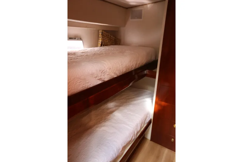 Slide: The Image of Bunk beds in 1981 Bertram Convertible yacht cabin, featuring wooden finishes and cozy bedding. - 60