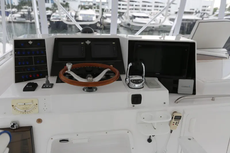 Slide: The Image of 1981 Bertram Convertible helm with steering wheel, navigation screens, and control panel. - 70