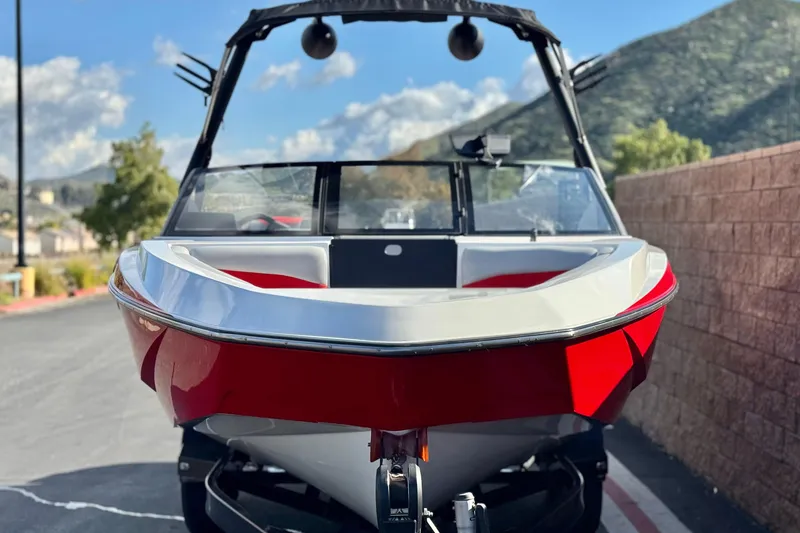 Slide: The Image of 2023 Axis T220 boat with red and white design, parked outdoors with scenic mountain backdrop. - 2