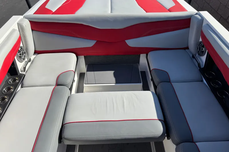 Slide: The Image of 2023 Axis T220 boat interior with red and gray seating, featuring cup holders and speakers. - 24