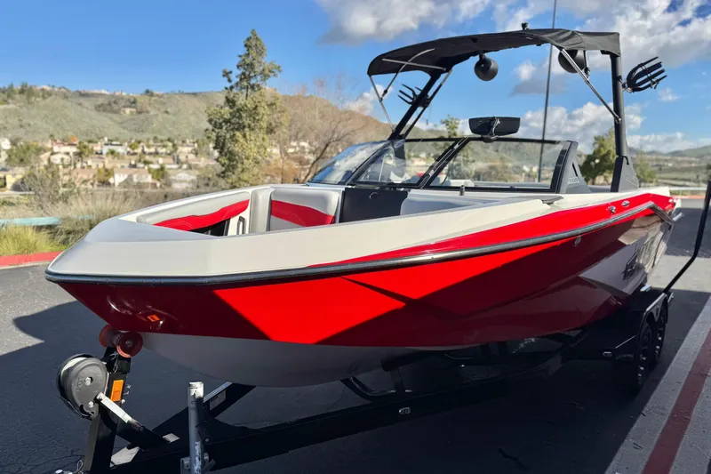 Slide: The Image of 2023 Axis T220 boat in vibrant red, parked on a trailer with scenic background. - 3