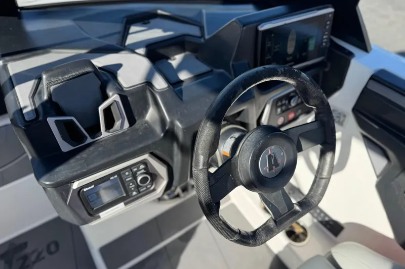 Slide: The Image of Steering wheel and dashboard of 2023 Axis T220 boat, featuring modern controls and display. - 33