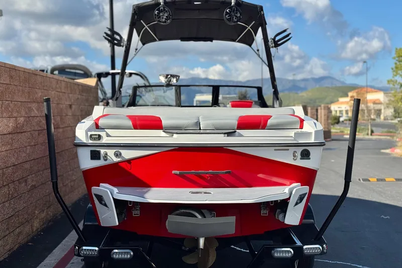 Slide: The Image of 2023 Axis T220 boat, red and white, parked outdoors with a scenic mountain backdrop. - 4