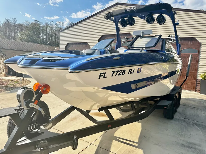 Slide: The Image of 2017 Malibu M235 boat on trailer, blue and white, sunny day. - 2