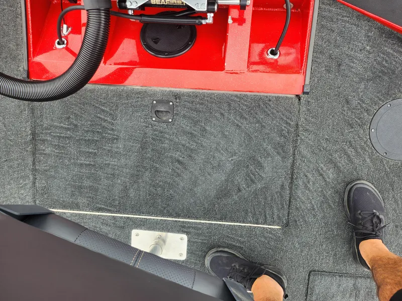 Slide: The Image of 2021 Caravelle Raptor 180 Bass boat interior with red accents and carpeted flooring. - 22