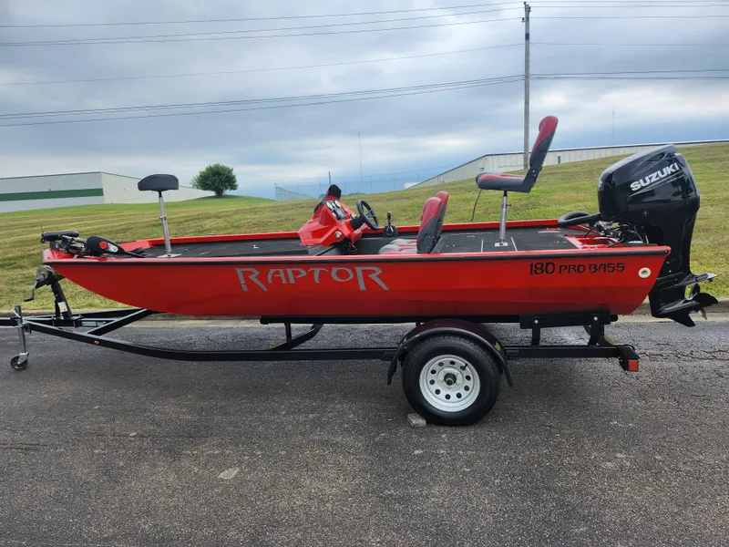 Slide: The Image of 2021 Caravelle Raptor 180 Bass boat with Suzuki motor on trailer, parked outdoors. - 4