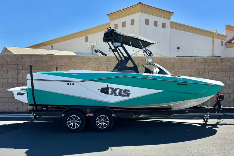 The Image of 2023 Axis T220 boat on trailer, teal and white design, parked outdoors. - 0