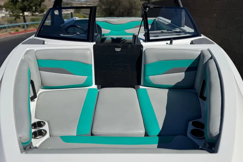 Slide: The Image of 2023 Axis T220 boat interior with teal and gray seating, cup holders, and windshield. - 10