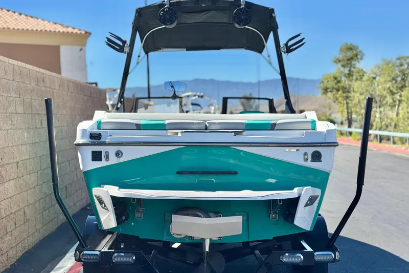 Slide: The Image of 2023 Axis T220 boat, teal and white, rear view on trailer, sunny day. - 4
