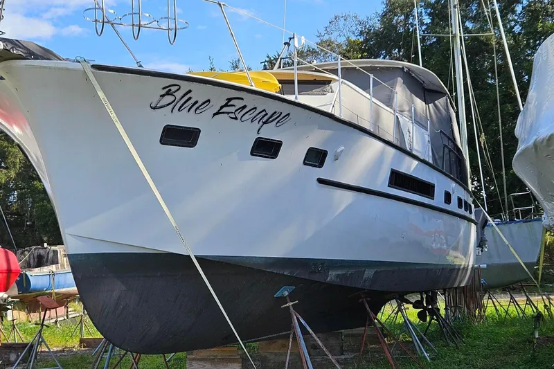 Slide: The Image of 1967 Hatteras yacht "Blue Escape" on land, surrounded by trees and other boats. - 27