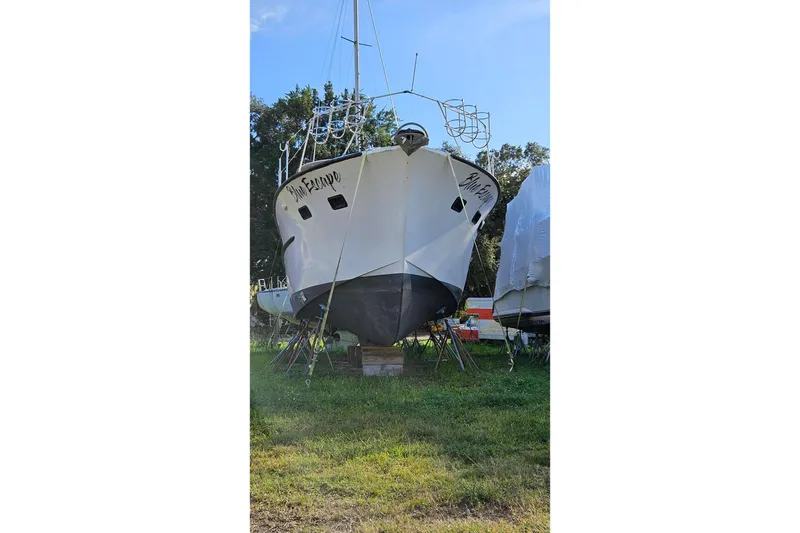 Slide: The Image of 1967 Hatteras boat on land, supported by stands, with clear blue sky background. - 29