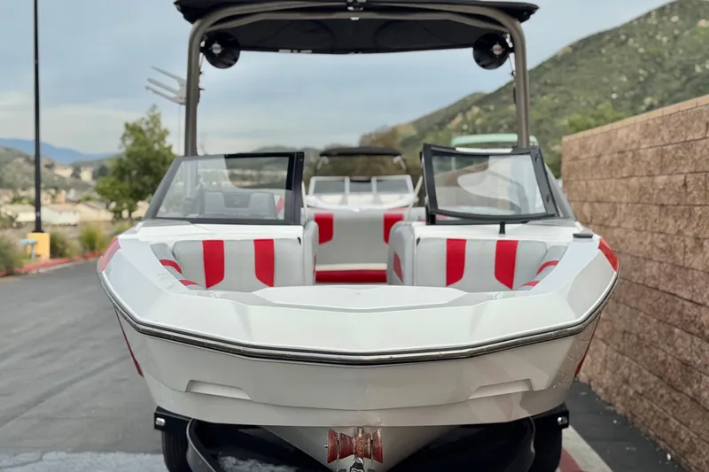 Slide: The Image of 2023 Malibu Wakesetter 21 LX boat with red and white interior, parked outdoors. - 2