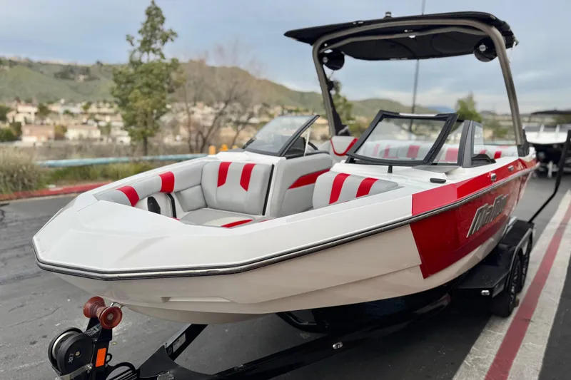 Slide: The Image of 2023 Malibu Wakesetter 21 LX boat with red and white interior, parked on a trailer. - 3