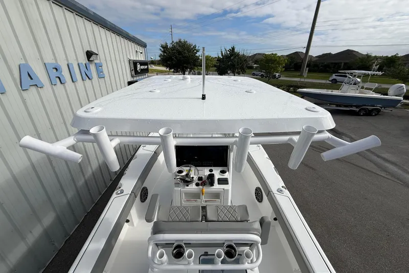 Slide: The Image of 2026 Blazer Bay Makaira 2600 boat with rod holders and console, parked near a marine shop. - 12