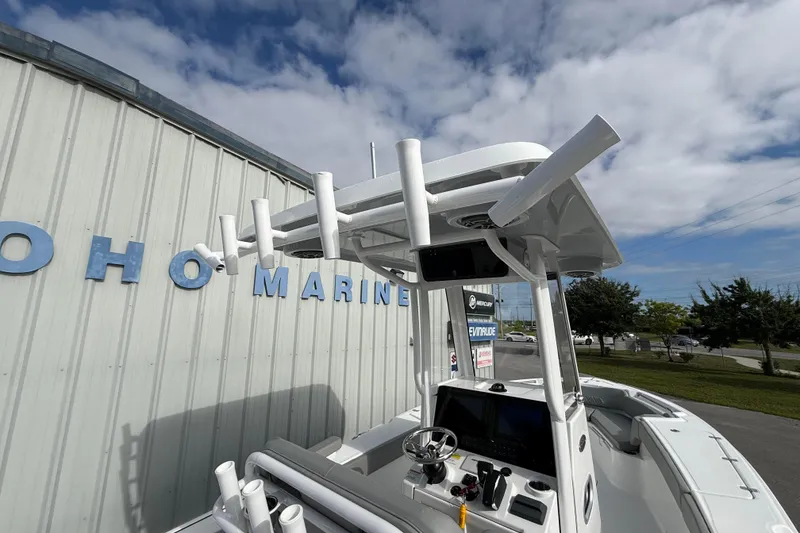 Slide: The Image of 2026 Blazer Bay Makaira 2600 boat with rod holders, parked near a marine building. - 27