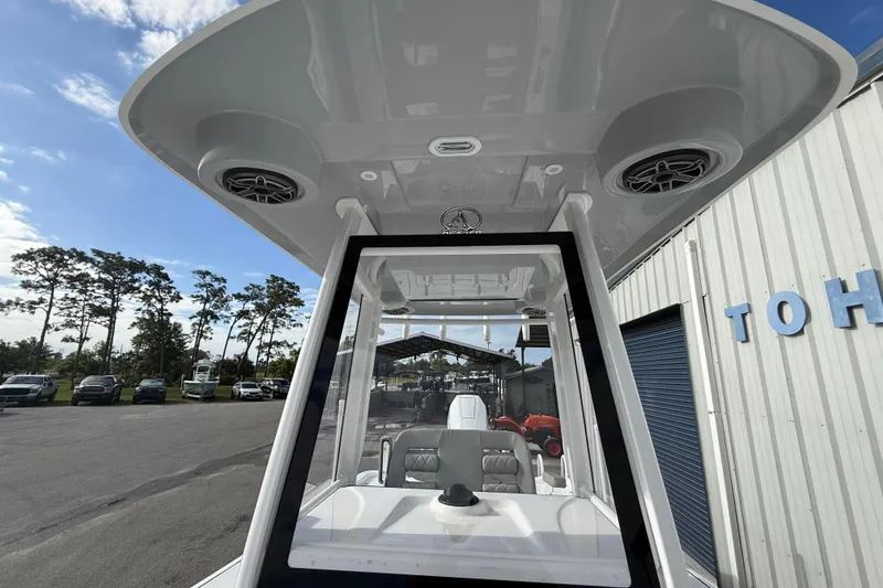 Slide: The Image of 2026 Blazer Bay Makaira 2600 boat with T-top speakers and console, parked outdoors. - 32