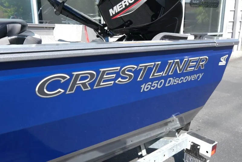 Slide: The Image of 2024 Crestliner 1650 Discovery Tiller boat, blue exterior, parked on trailer. - 6
