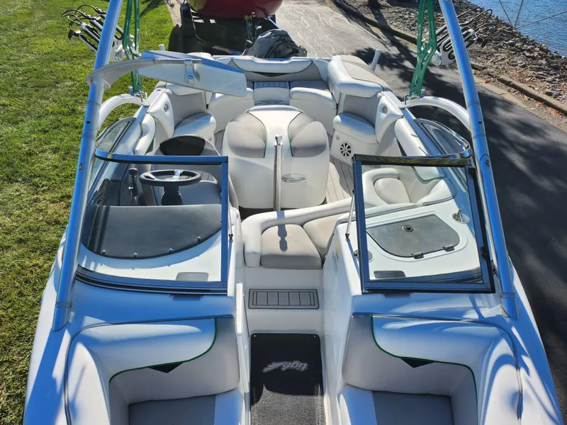 Slide: The Image of 2007 Tigé 22i boat interior with white seating and open windshield, parked near water. - 18