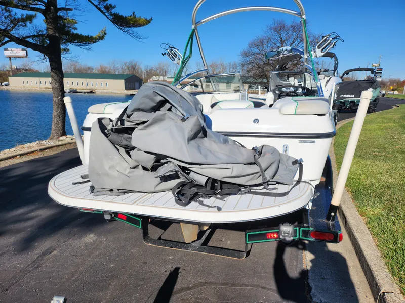 Slide: The Image of 2007 Tigé 22i boat with cover on swim platform, parked near a lake. - 2