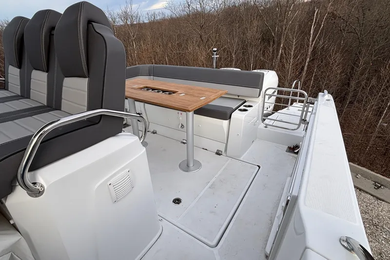 Slide: The Image of 2022 Jeanneau Leader 9.0 CC boat interior with seating and table, surrounded by trees. - 10