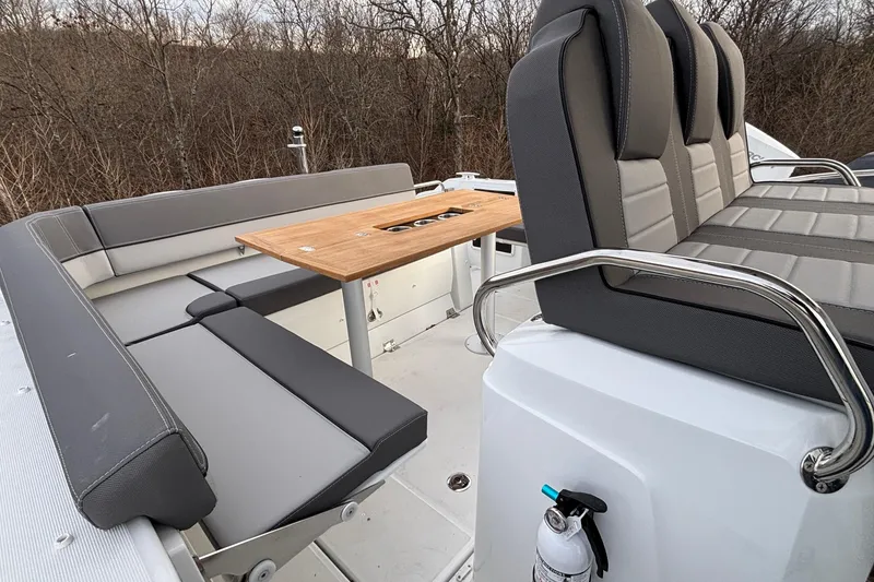 Slide: The Image of 2022 Jeanneau Leader 9.0 CC boat interior with gray seating and wooden table. - 13